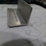 Sheet metal part bent at a 90-degree angle, resembling a bracket with clean edges and precision.