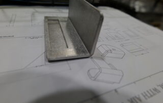 Sheet metal part bent at a 90-degree angle, resembling a bracket with clean edges and precision.