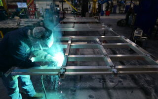 Welder fitting an aluminum frame for datacenters